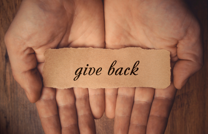  Hands together with a piece of paper saying give back